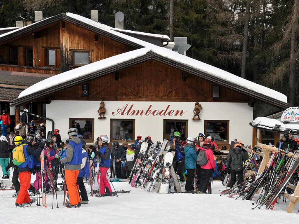 Skihütte „Almboden“ mit abgestellten Skiern davor.